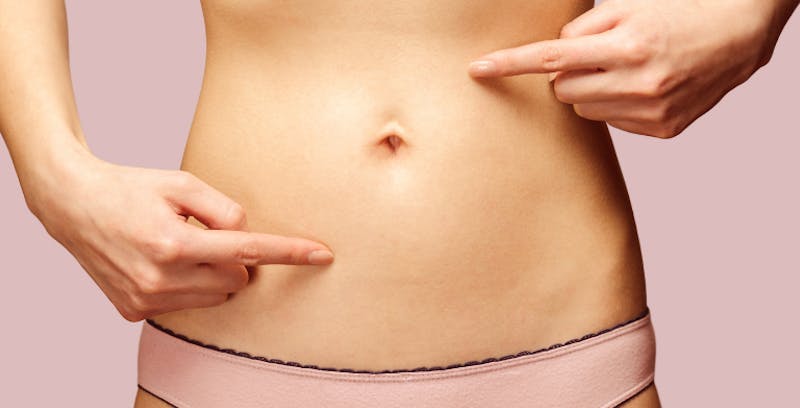 close up of woman pointing to different points on her stomach
