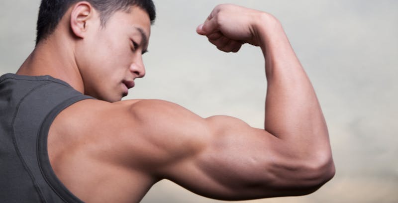man flexing his muscles in a gray tank top