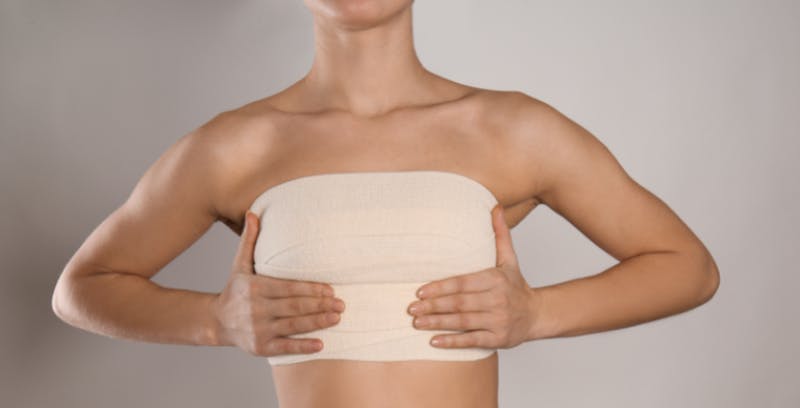 woman in a tan chest wrap holding her chest