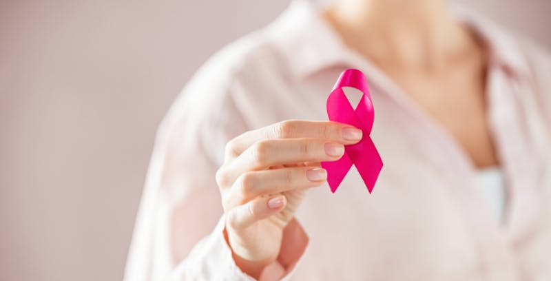someone holding a Breast Cancer Awareness pink ribbon in their hand