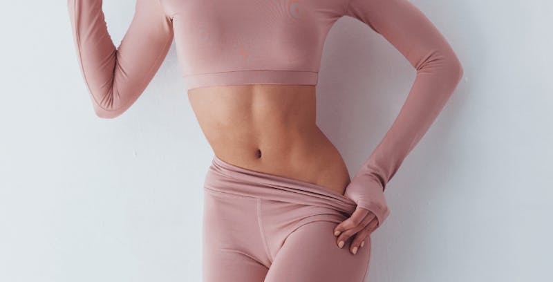 close up of woman's abdomen in a pink spandex shirt and matching yoga pants