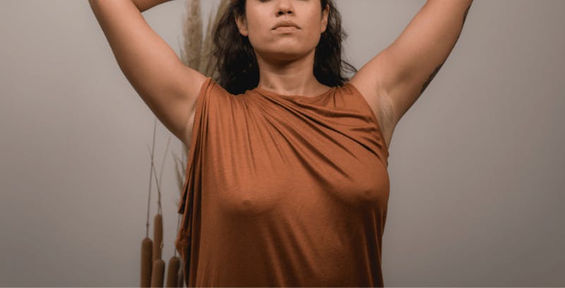 woman with dress and no bra on with arms up in air