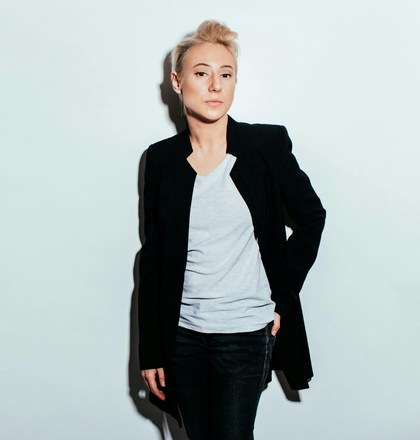 short haired blond woman in black jacket and white shirt posing for a picture