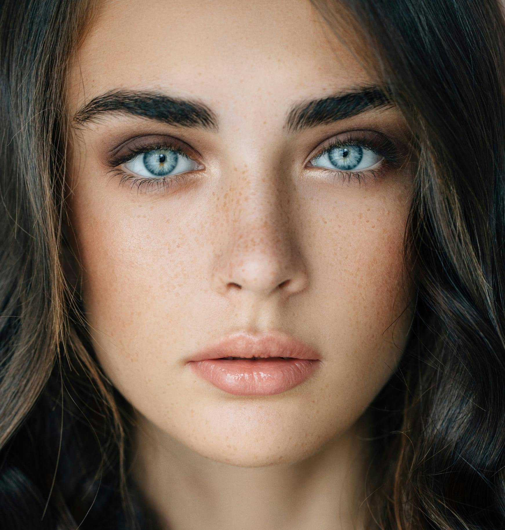 close up of a woman's face with freckles and blue eyes