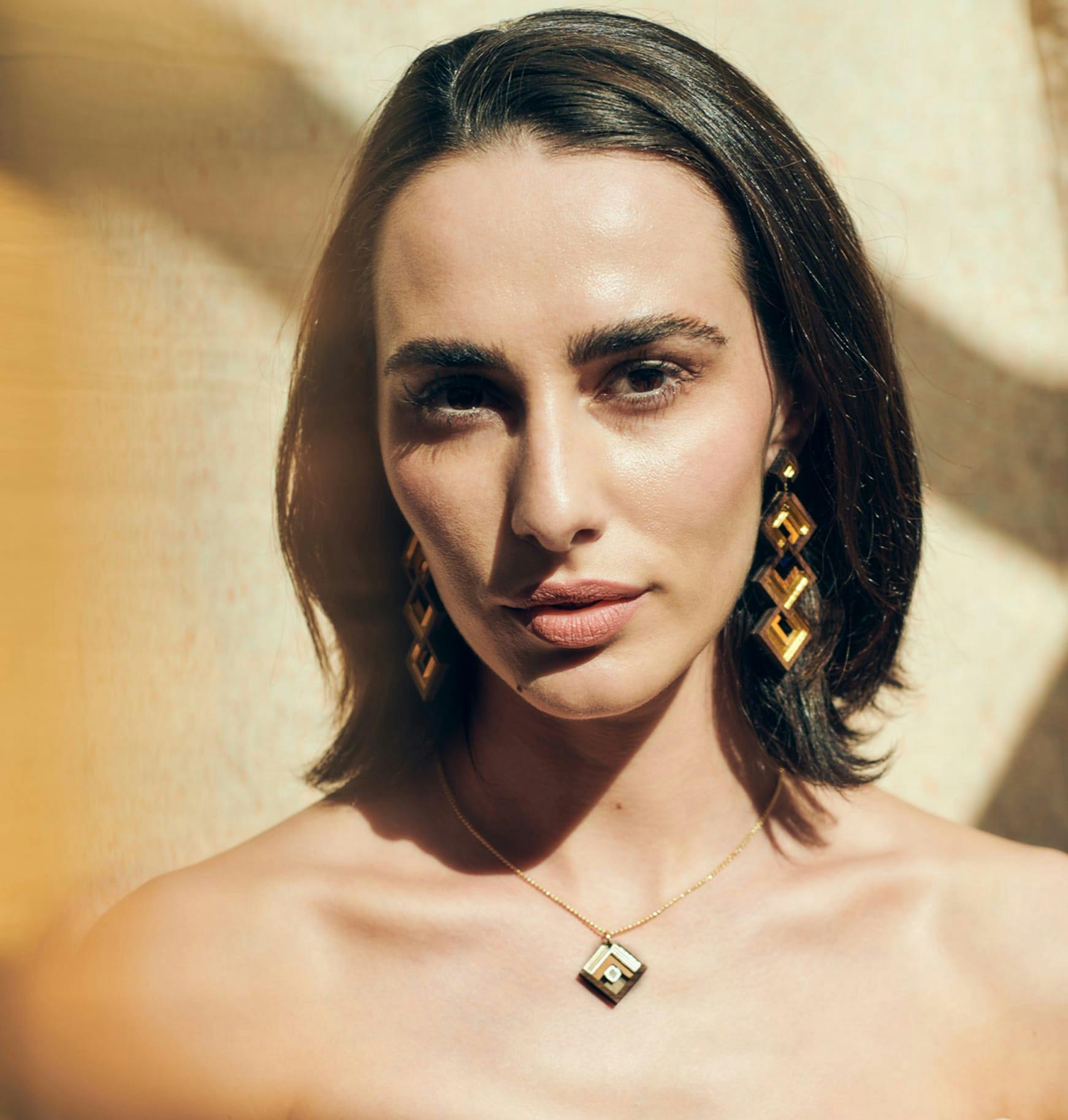woman with a necklace and earrings posing for a picture