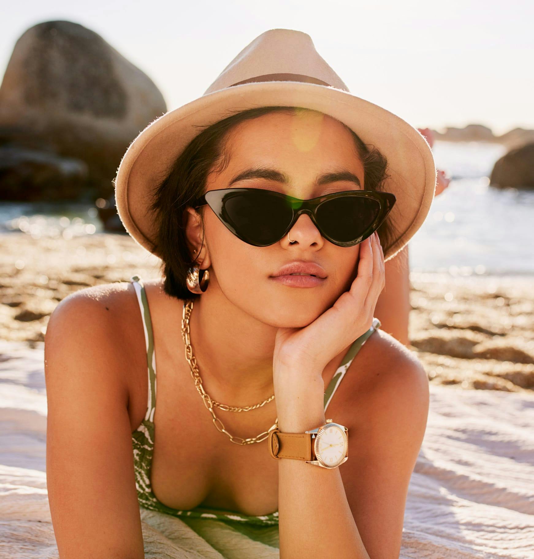 woman laying on the beach wearing a hat and sunglasses