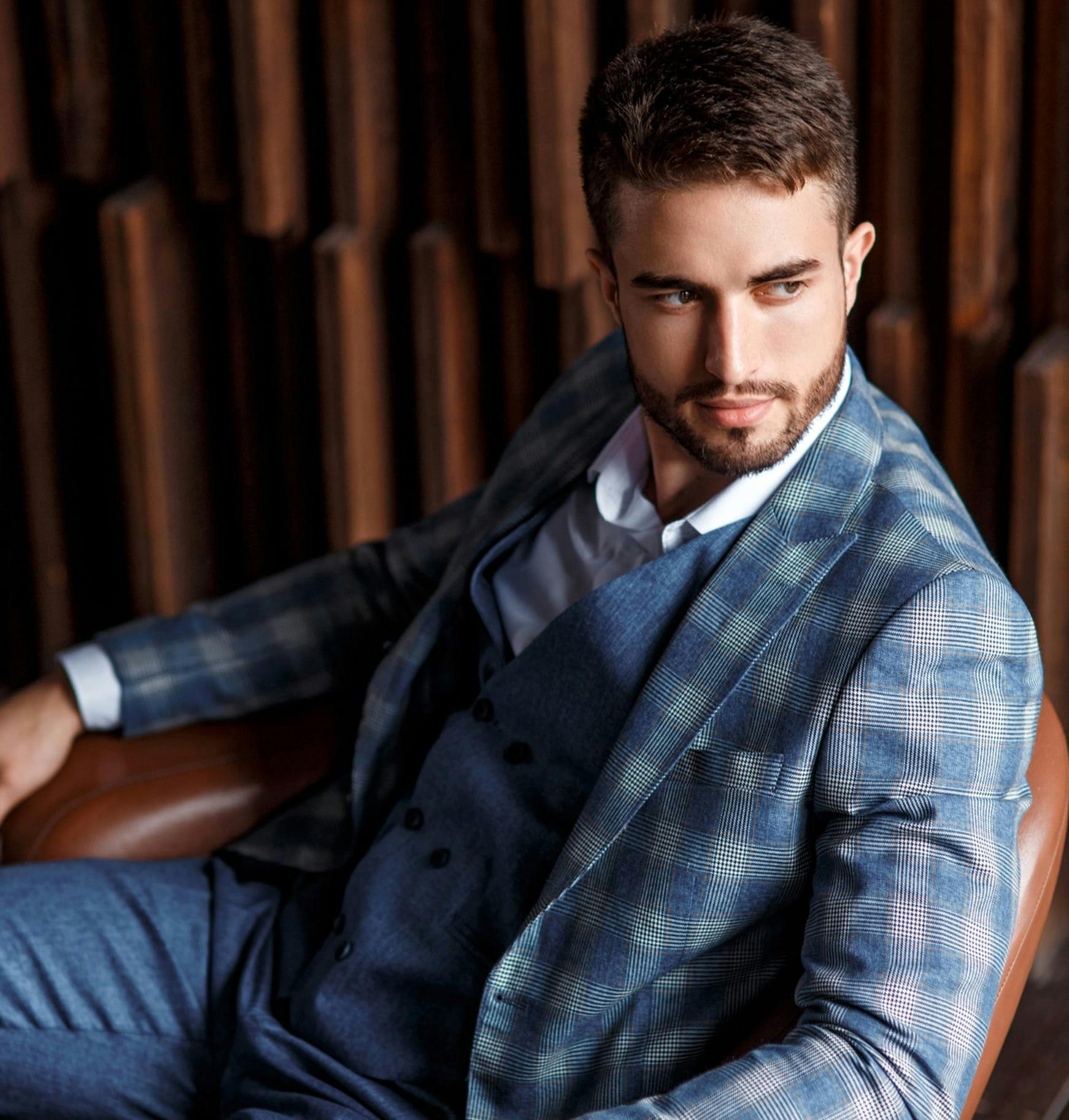 man in a suit sitting in a brown leather chair