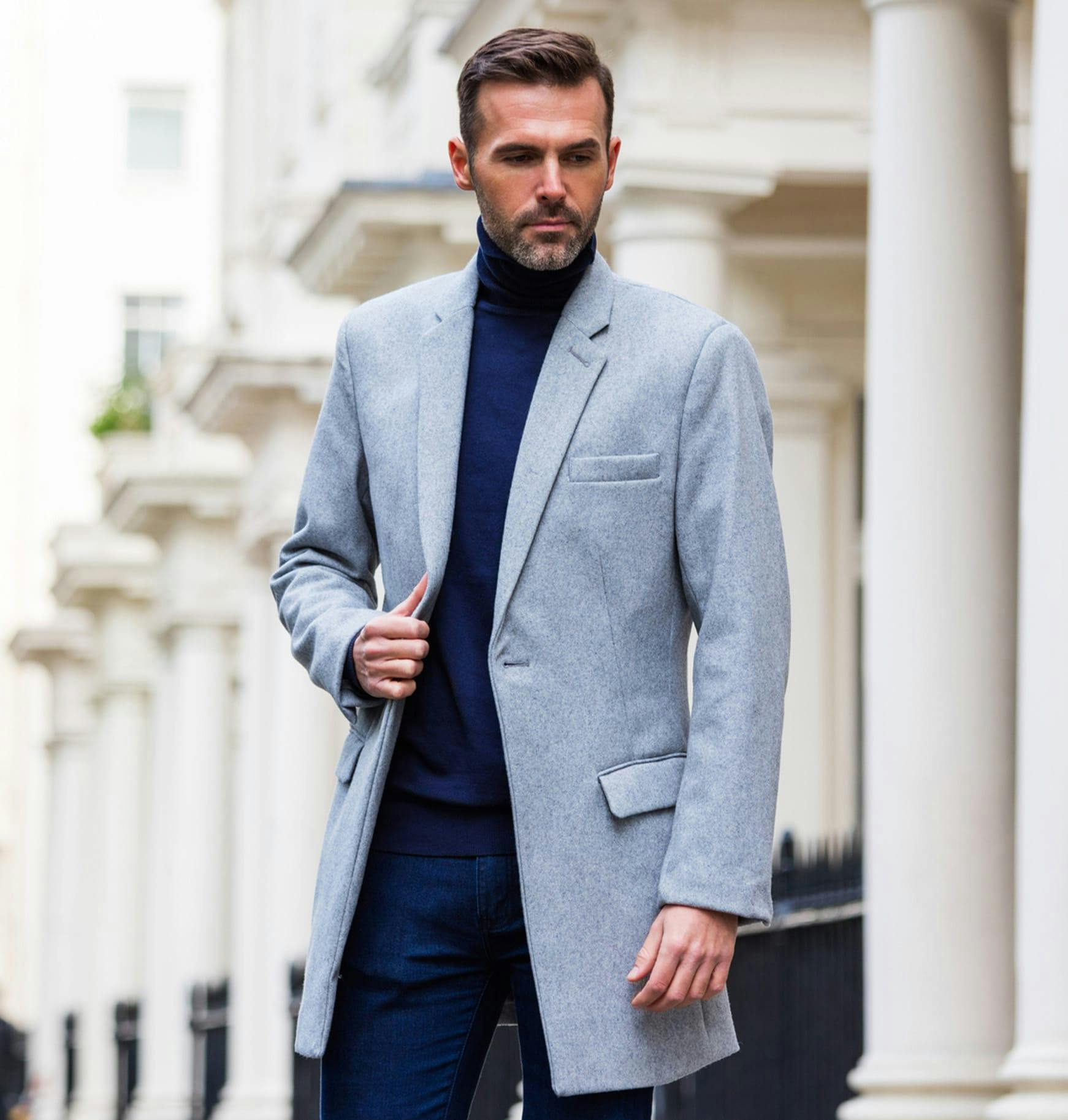 man in a gray coat and blue turtleneck sweater