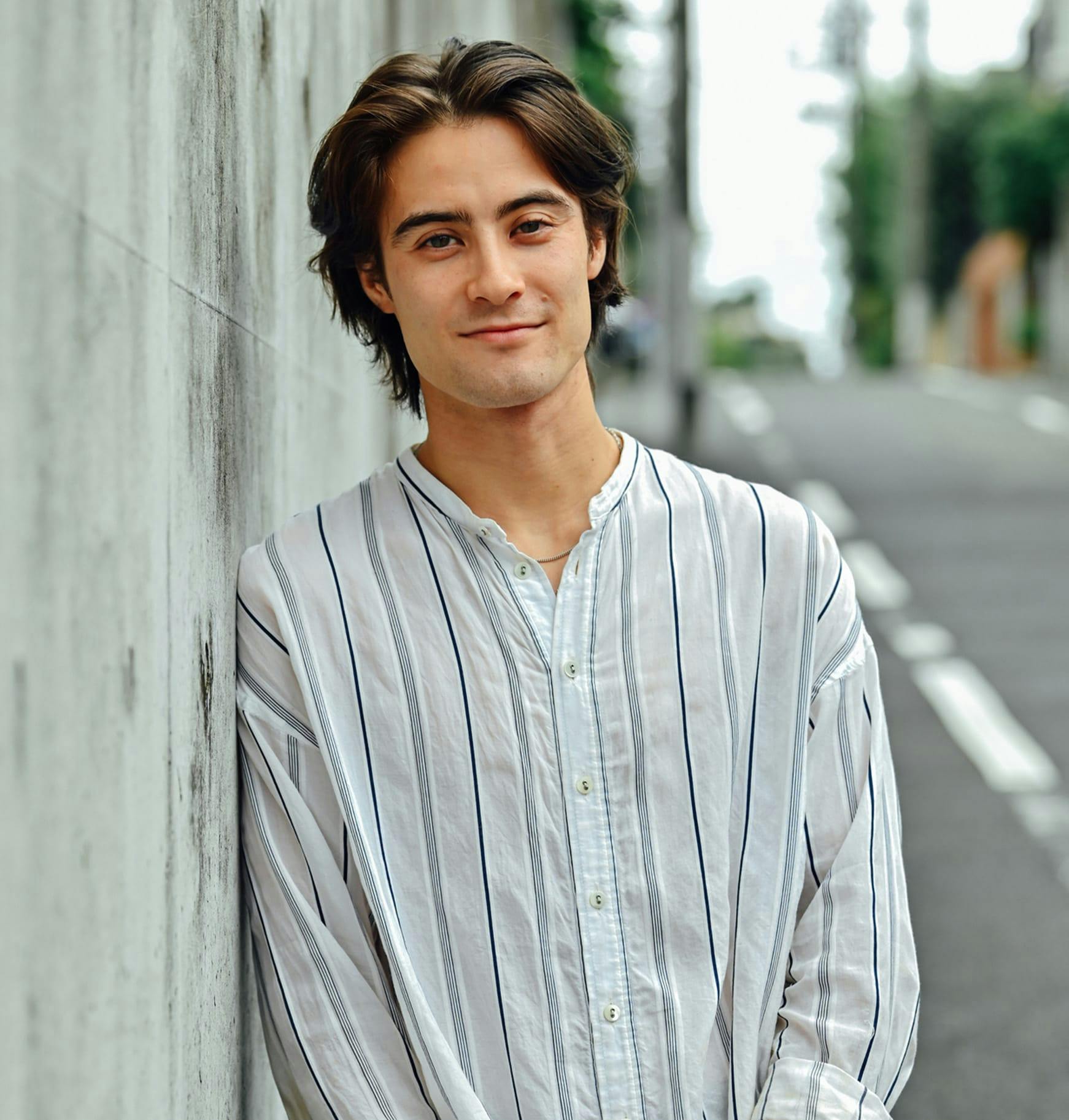 man leaning against a wall in a city street