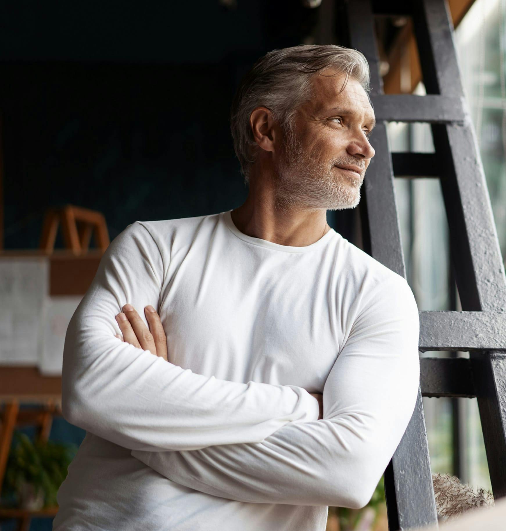 a man standing in front of a ladder with his arms crossed