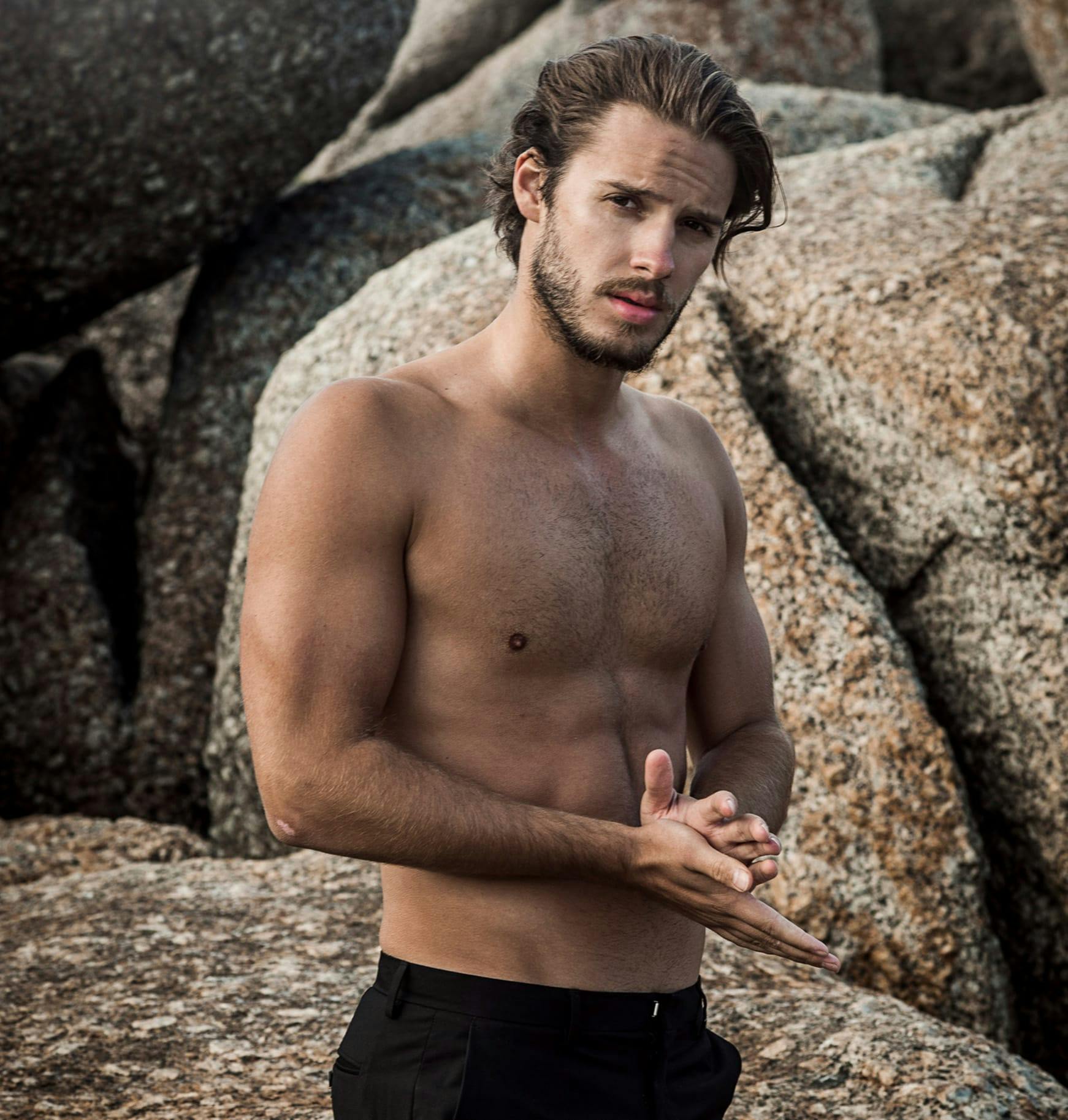 a man standing in front of a rock without shirt