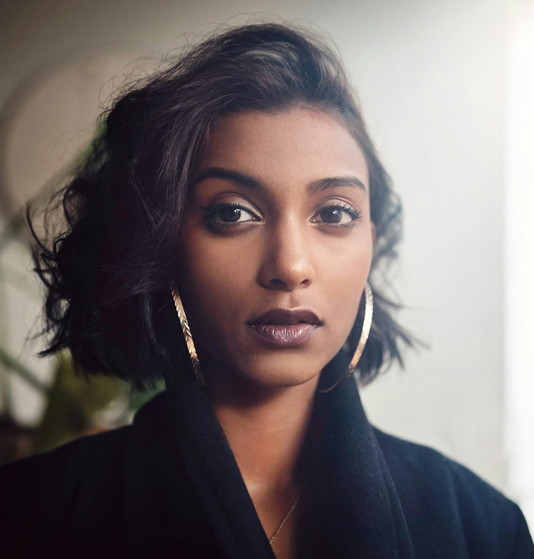 a woman in a black robe and earrings posing for camera