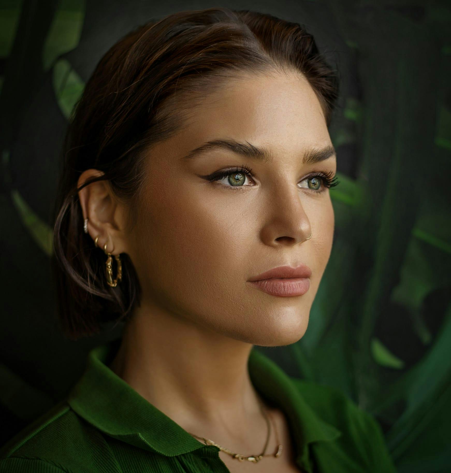 woman with green shirt and earrings looking posing for camera