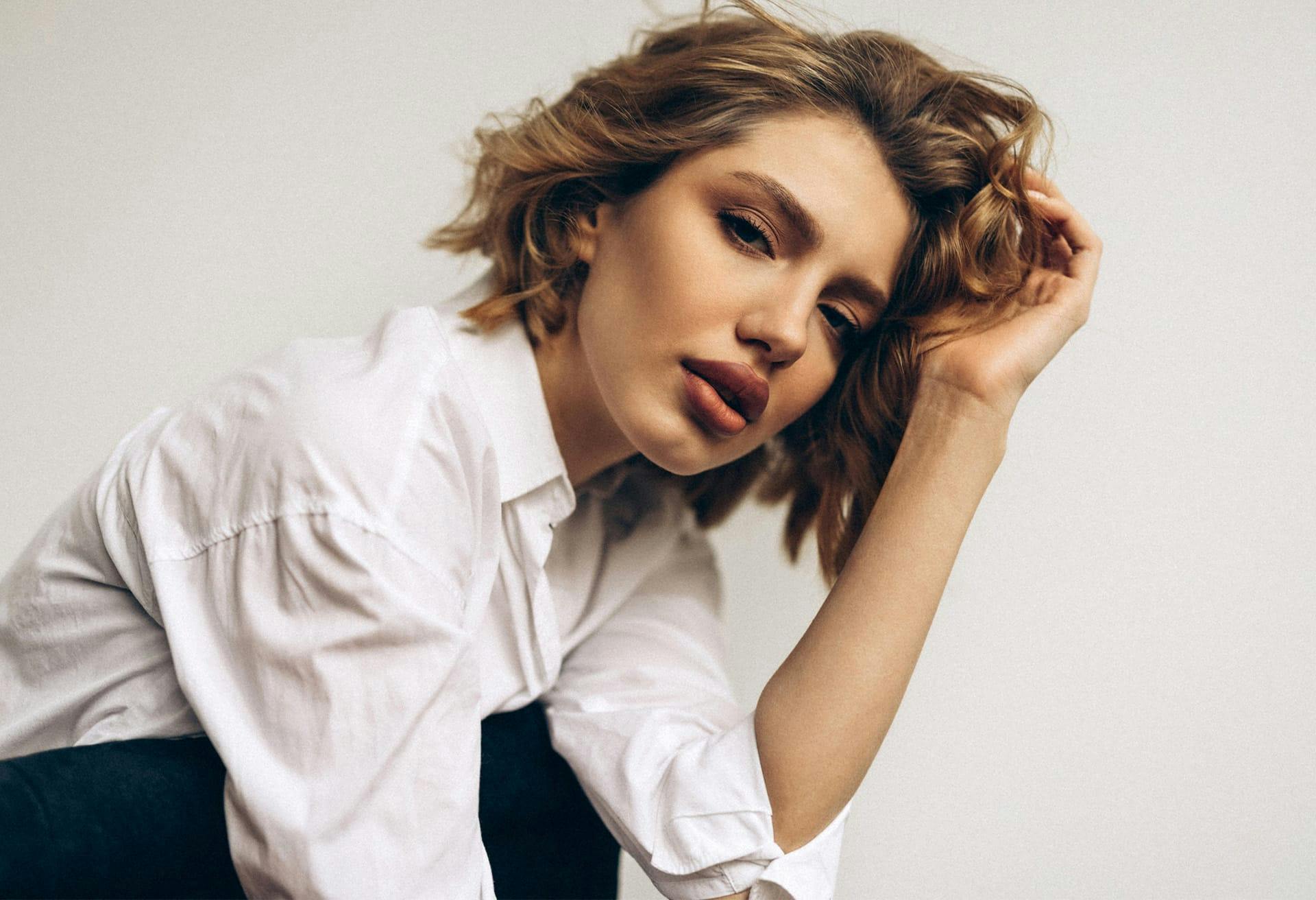 Woman with shoulder length wavy hair wearing a white button up top