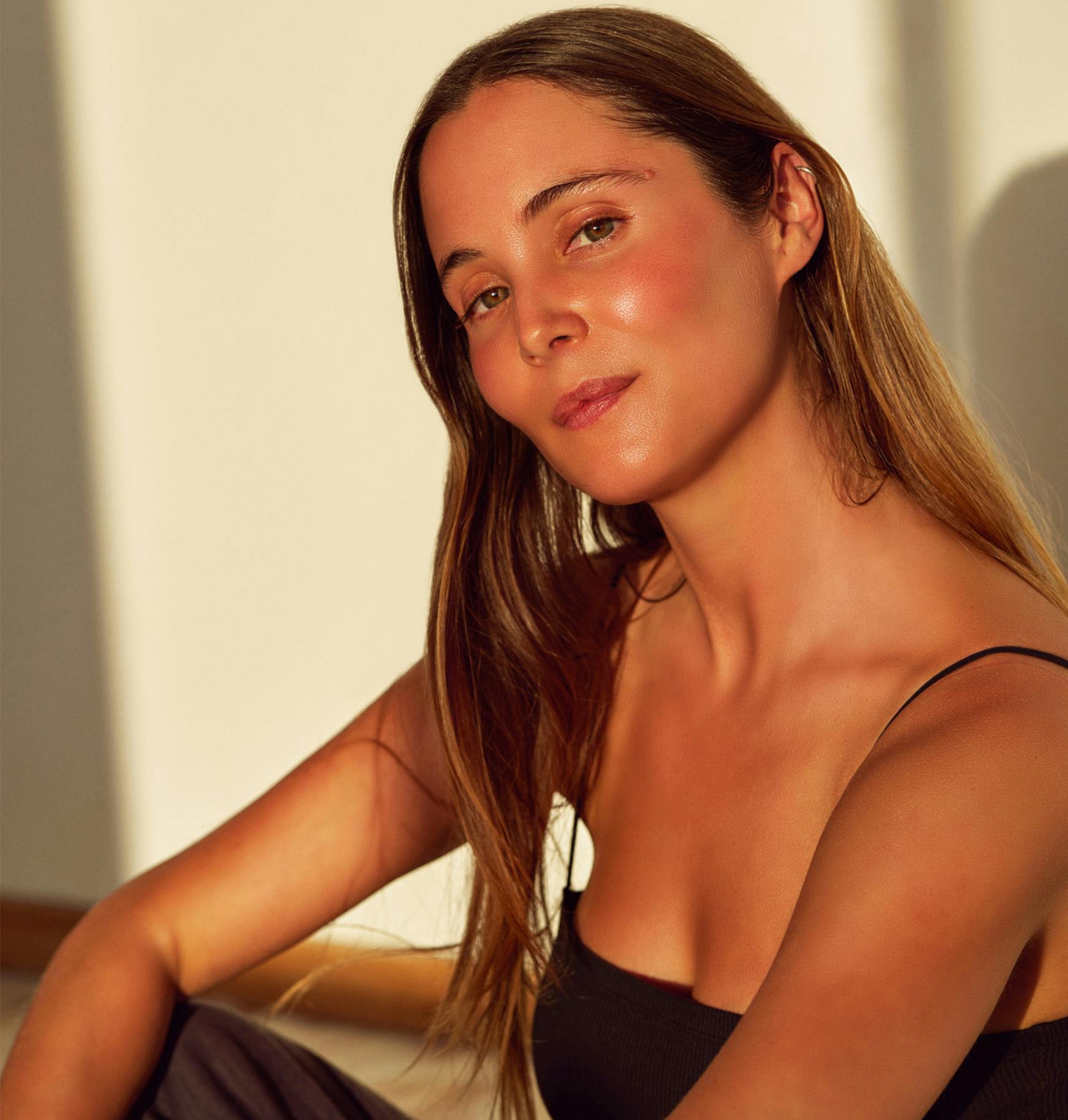 a woman sitting on a couch with a black tank top