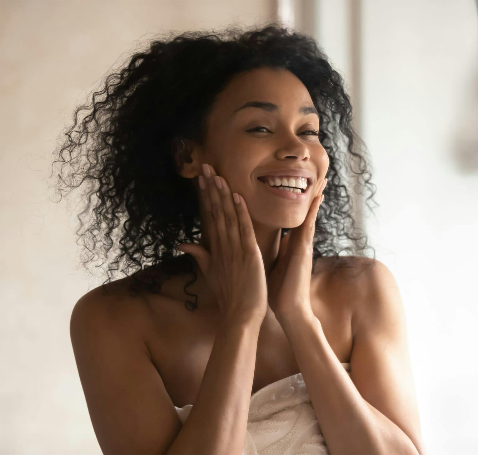 woman in towel cupping her face in her hands