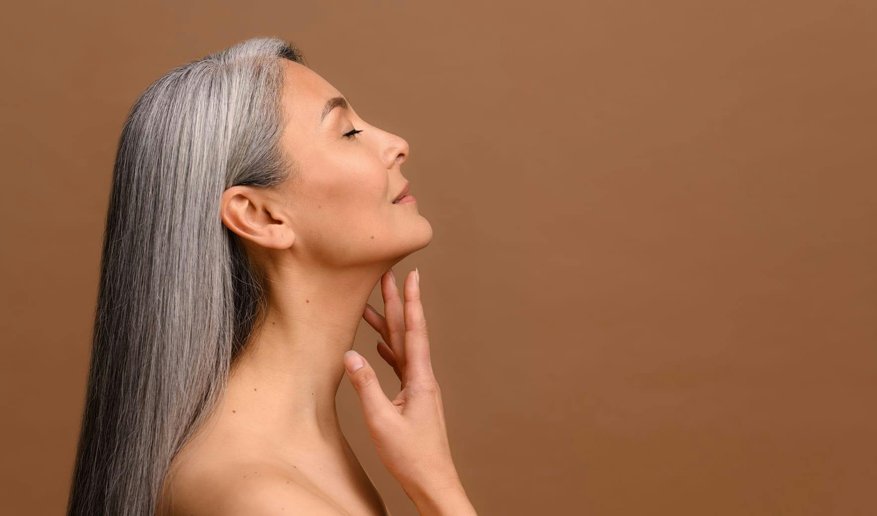 woman with gray hair touching her chin