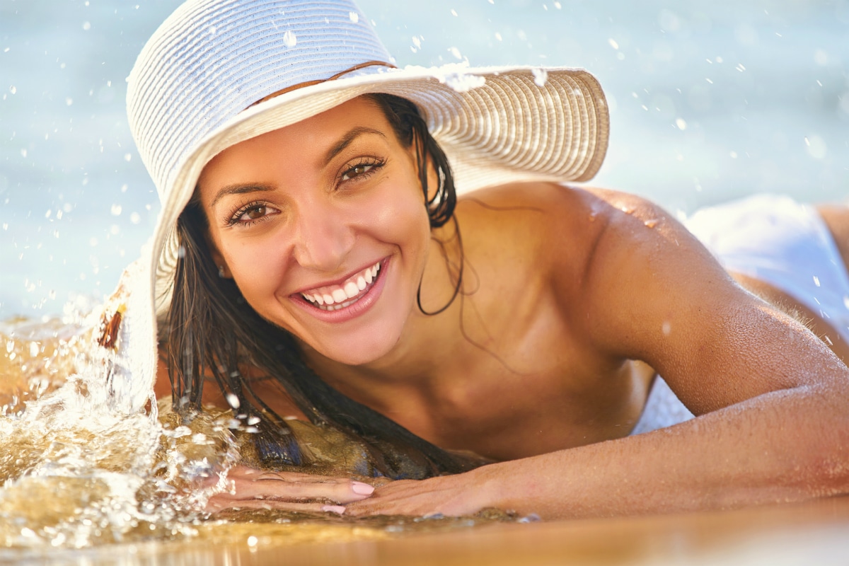 woman laying on beach in sunhat