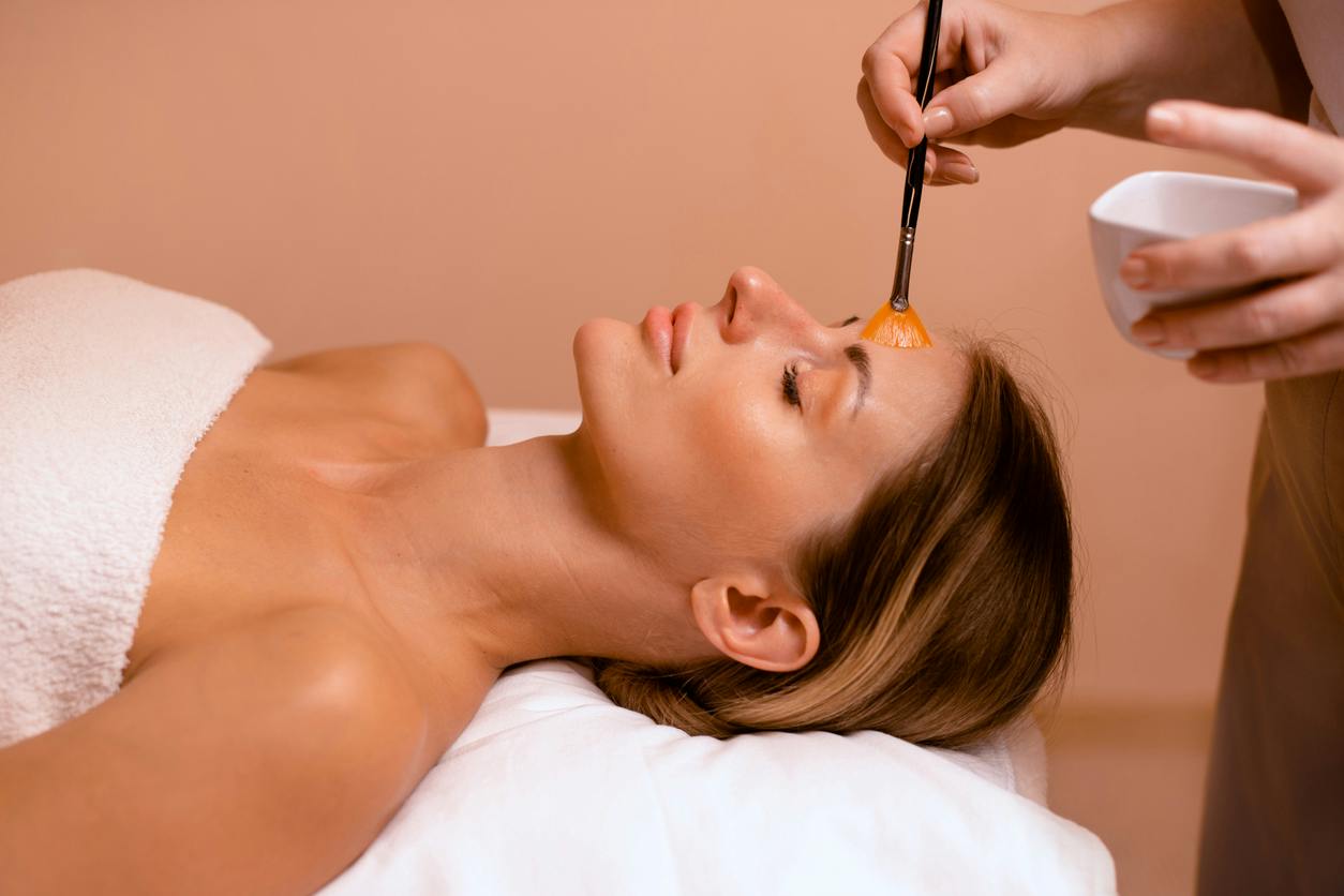 Patient lying back while a provider applies a skin treatment to her face with a brush