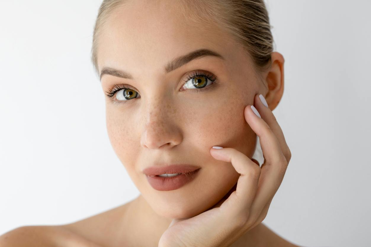 Woman with glowing skin resting her hand against her face