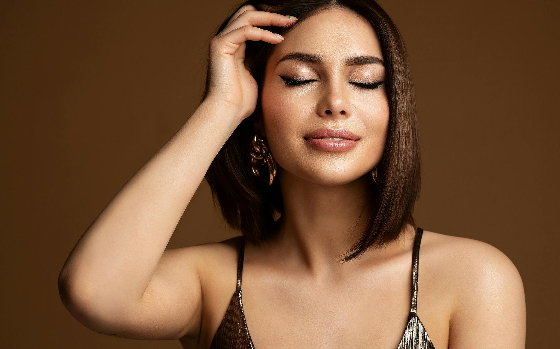 Beautiful woman brushing hair back, smiling with eyes closed