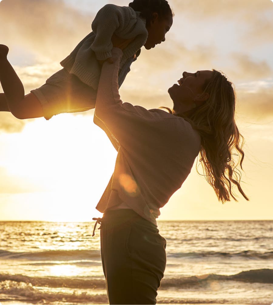 Mother holding up child at the beach