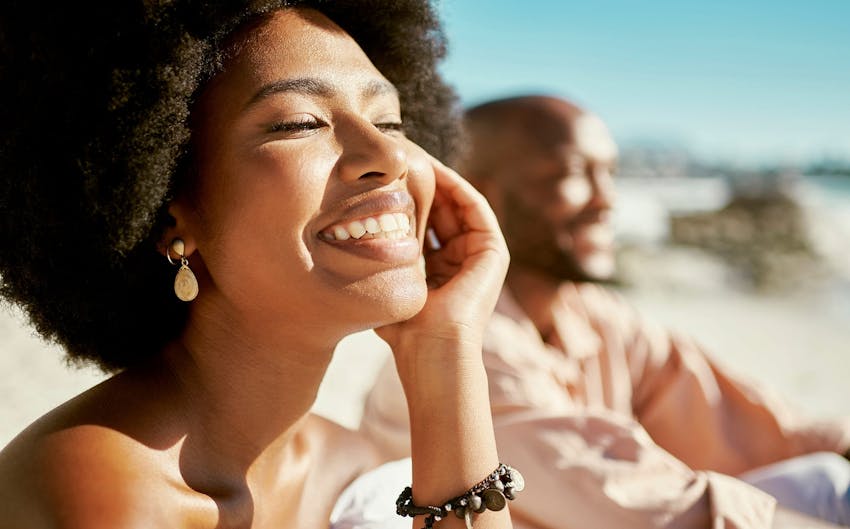 Woman smiling next to her husband at the beach