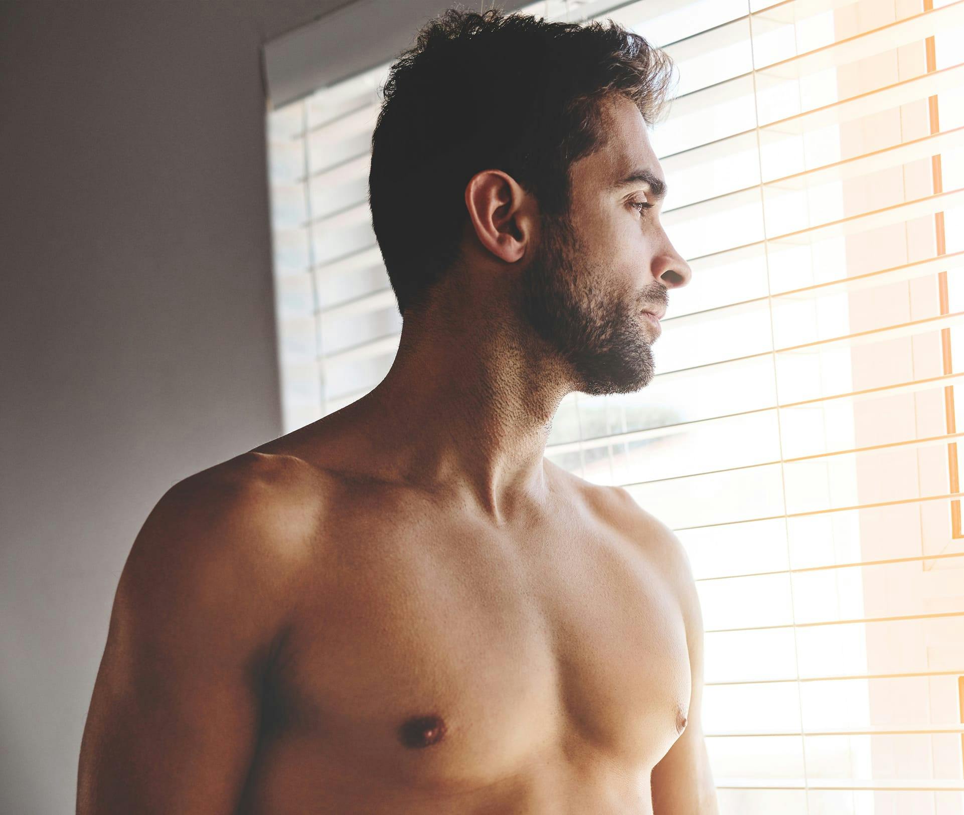 shirtless man looking out the window