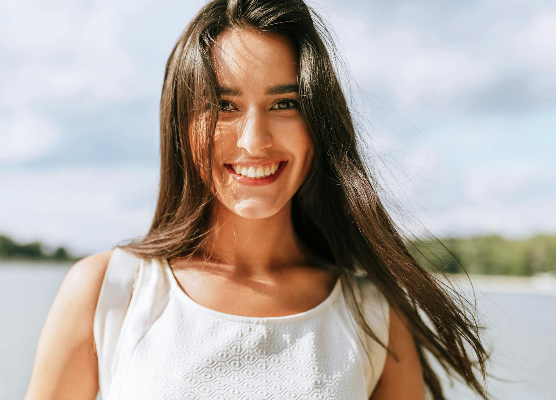 Woman with long brown hair wearing a white shirt