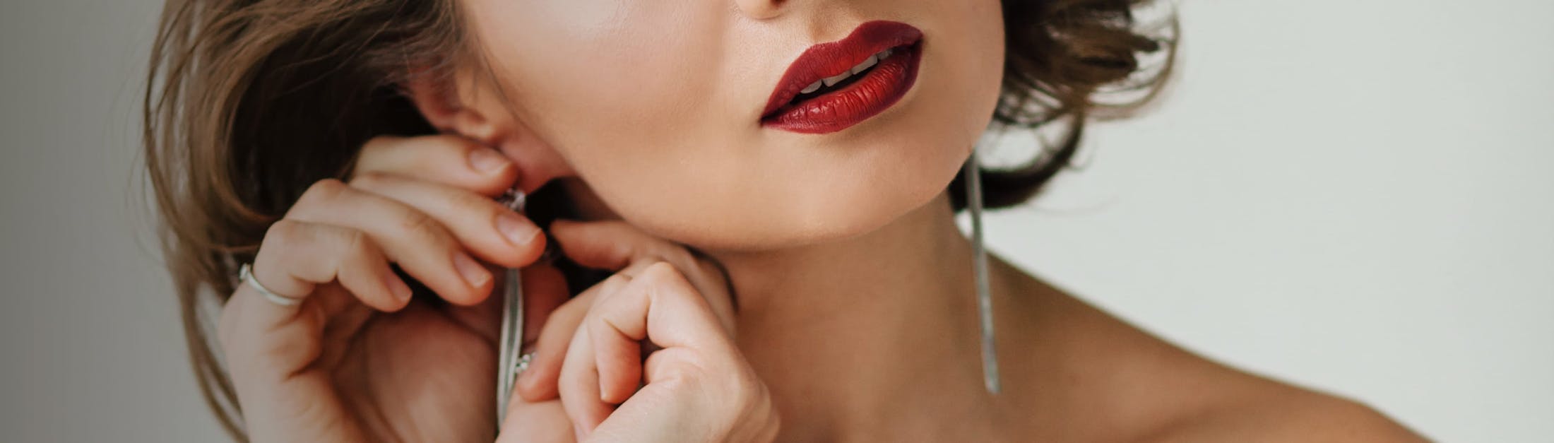 Glamorous woman putting on earrings