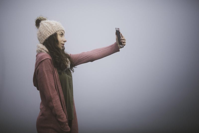 a woman in a red jacket is holding a cell