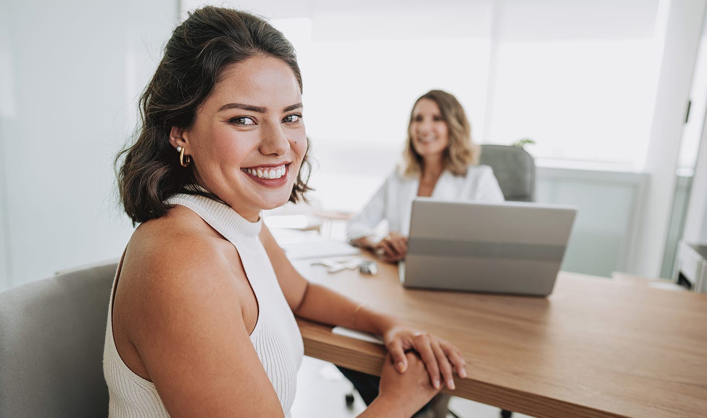 woman smiling next to a laptop