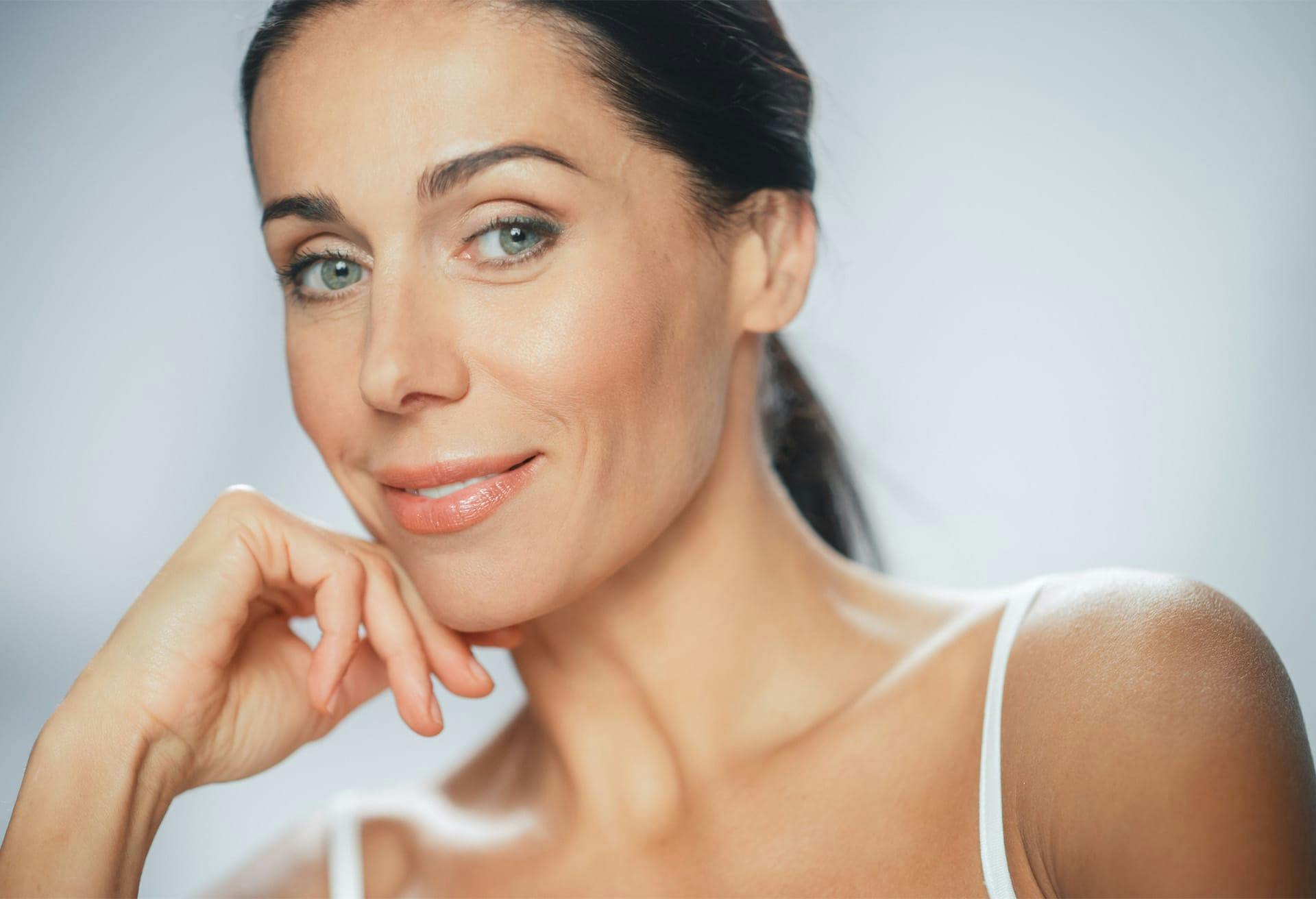 woman smiling at camera with hand on chin