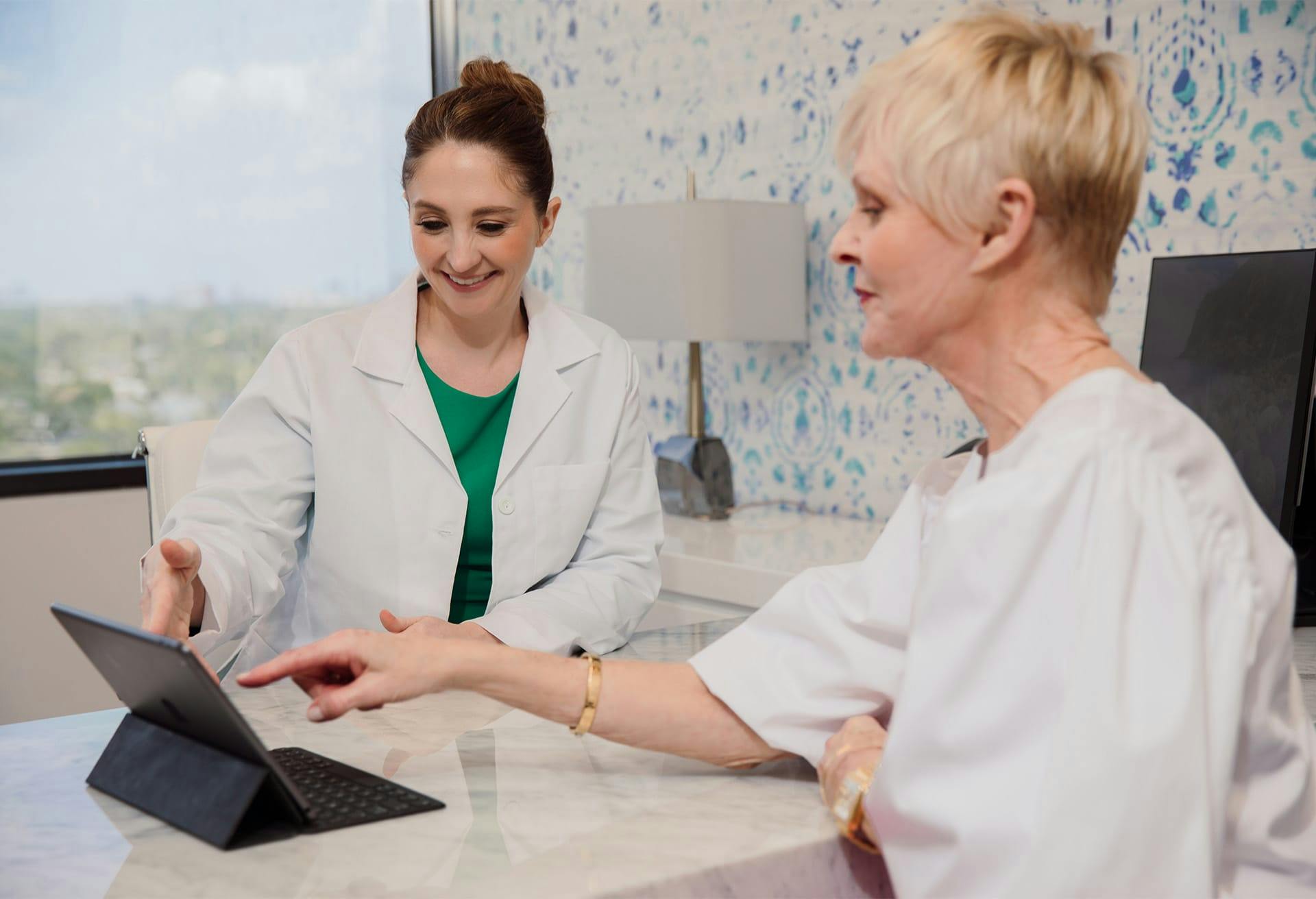 two people at a desh pointing at a tablet