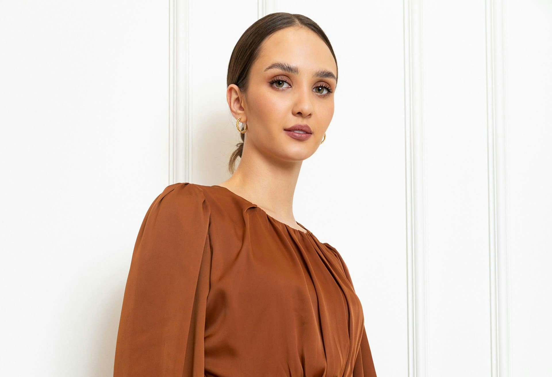 woman in rust colored blouse looking at camera