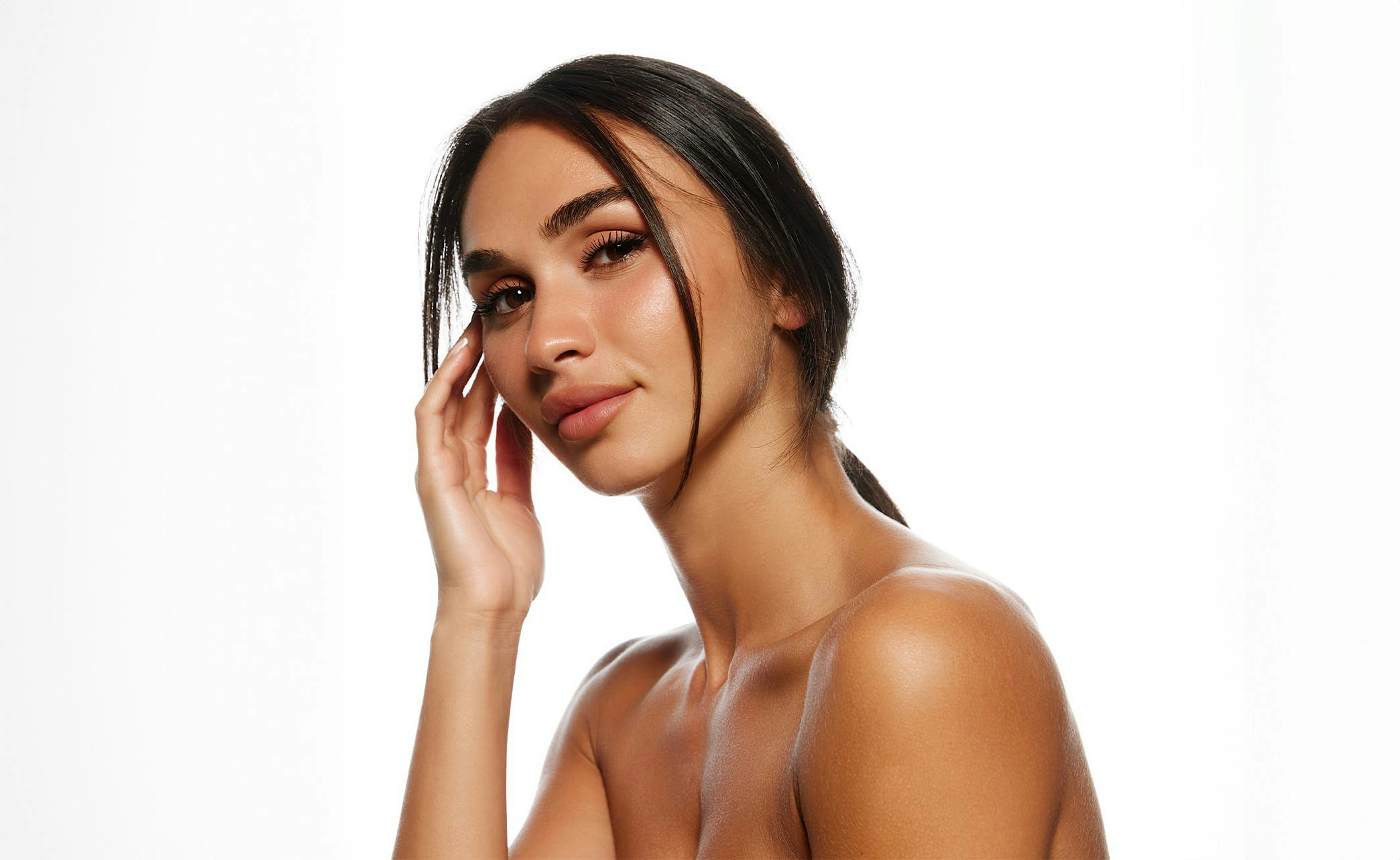 woman with dark hair touching the side of her face