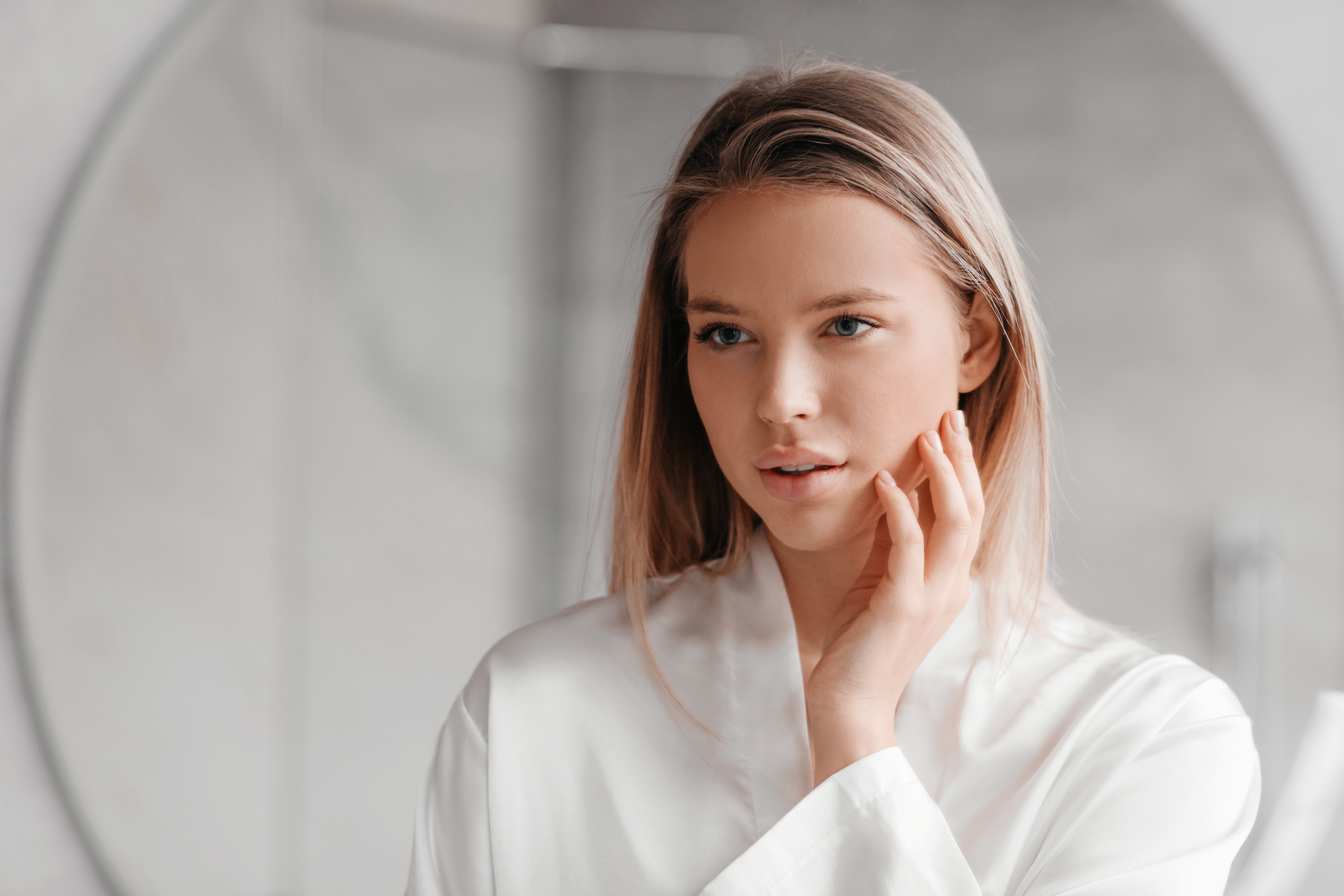 woman looking in mirror and touching her face