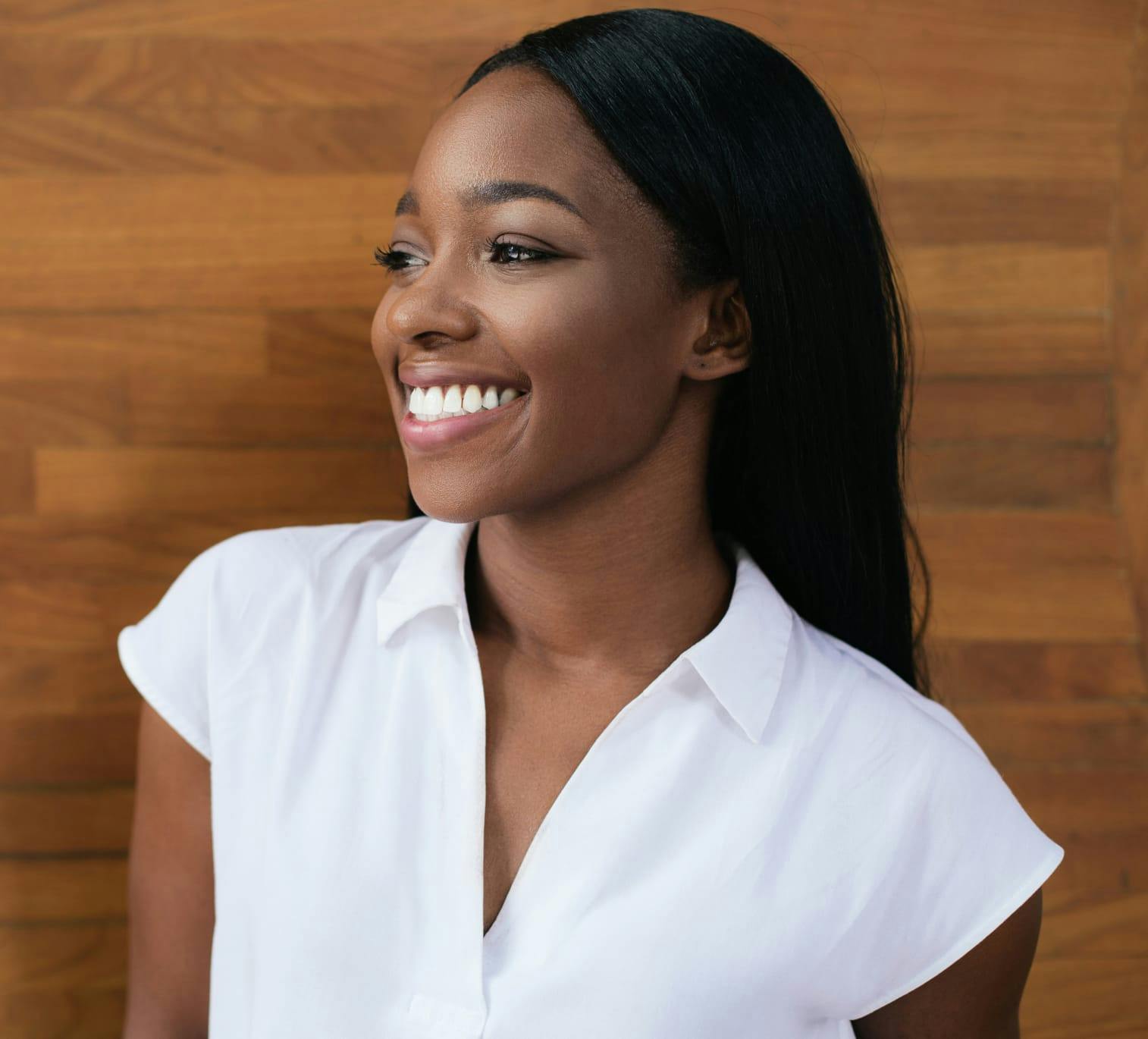 Woman smiling and standing in front of wooden wall