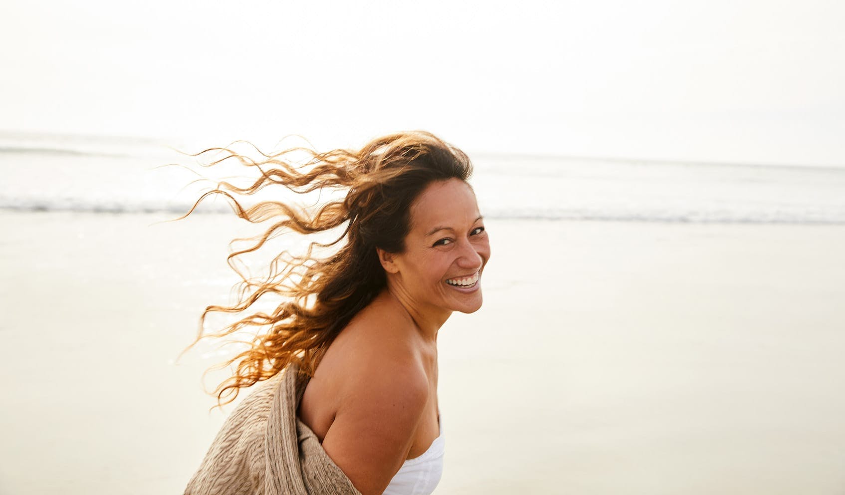 woman smiling and enjoying the beach