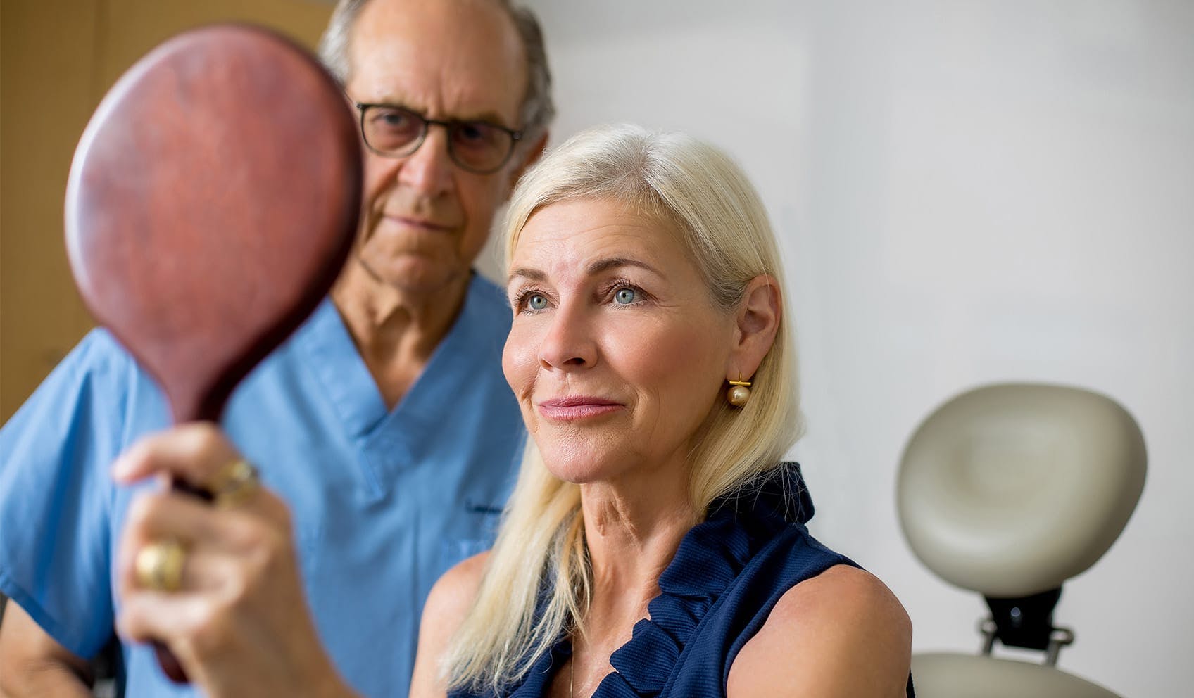 Patient holding up mirror and looking at her face