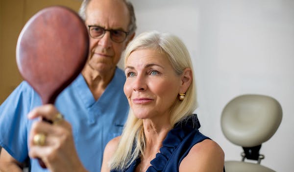 Patient holding up mirror and looking at her face