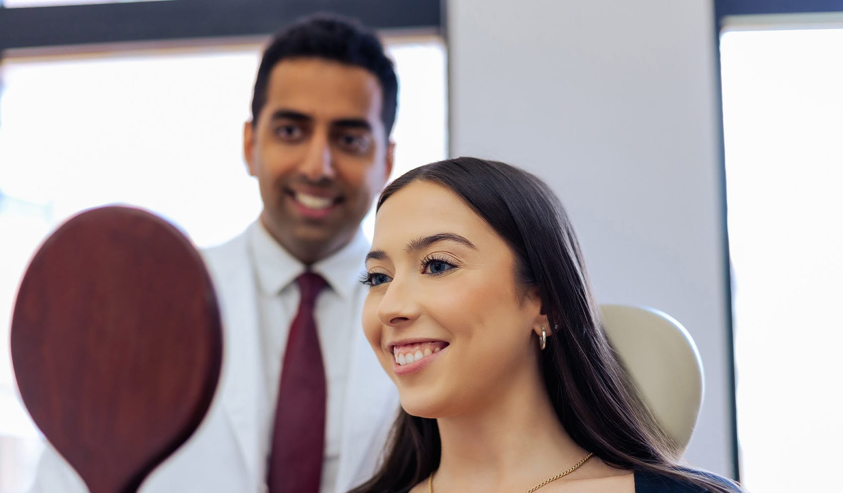 Doctor holding up mirror to smiling patient