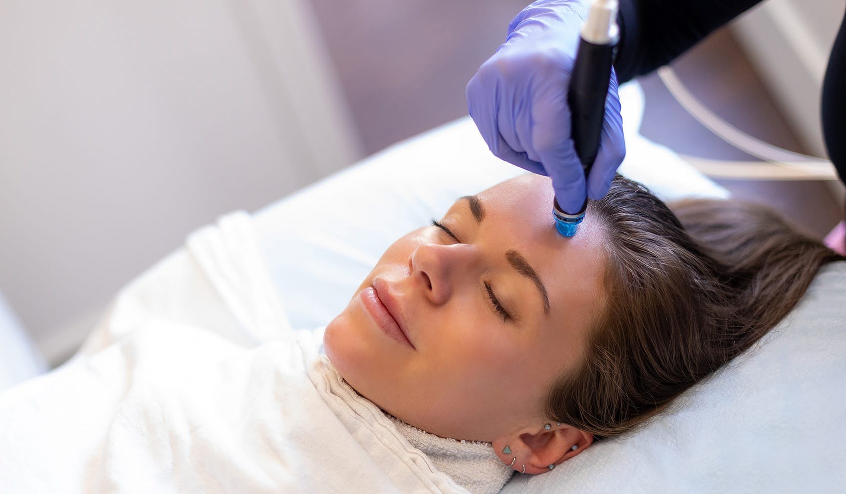woman smiling and receiving hydrafacial treatment
