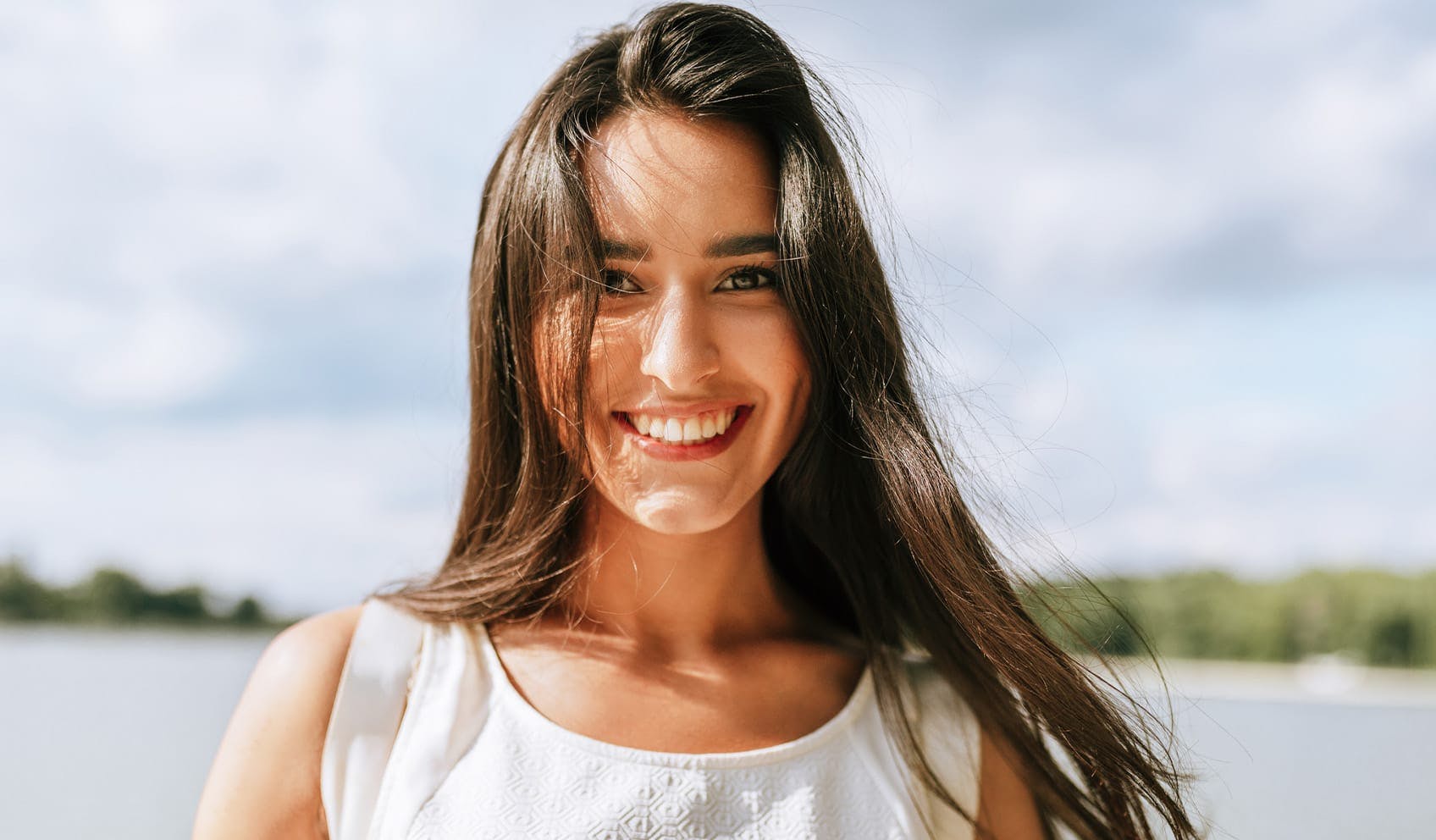 woman smiling and standing in front of lake