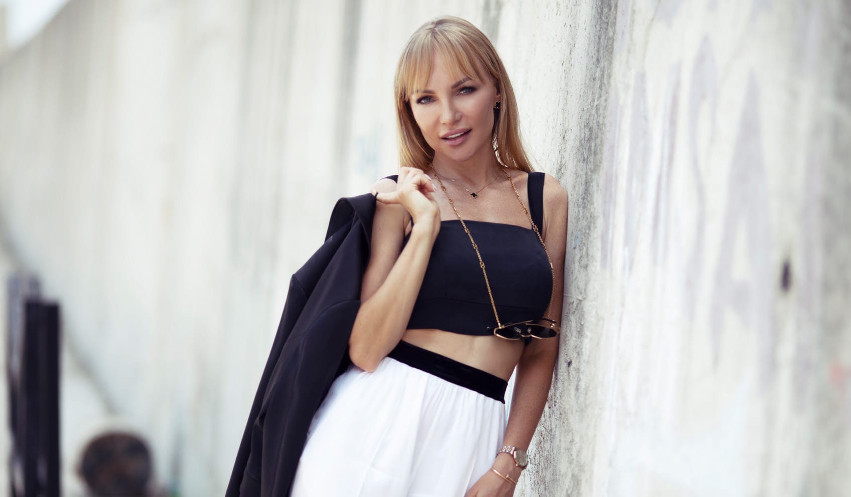 beautiful woman leaning against wall and holding coat over shoulder