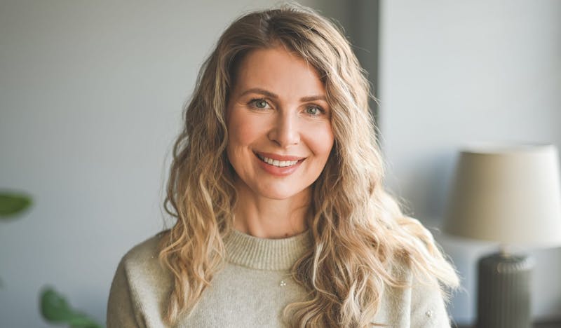 woman smiling and standing in front of lamp