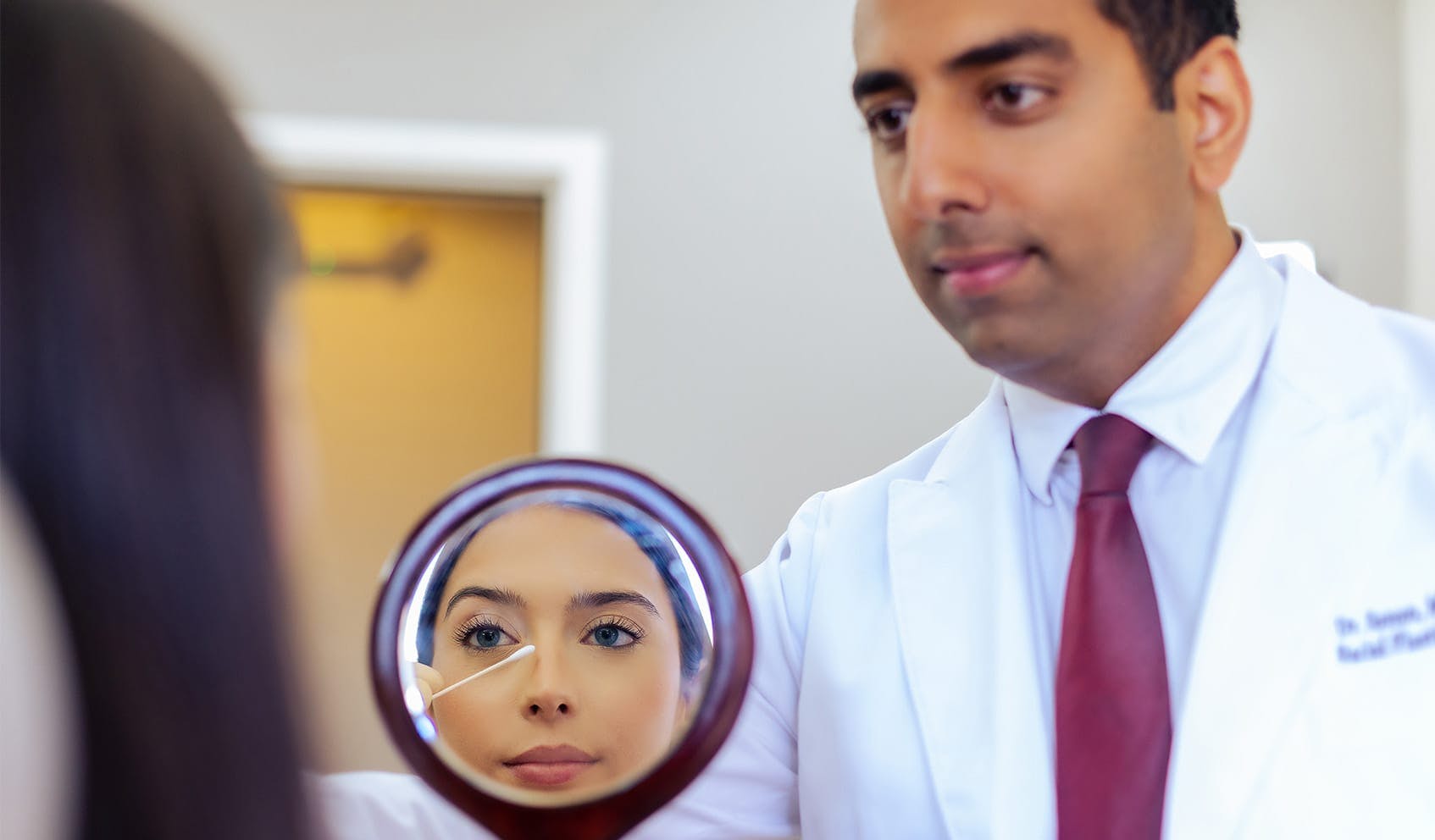 Dr. Ashkay Sanan holding mirror for patient