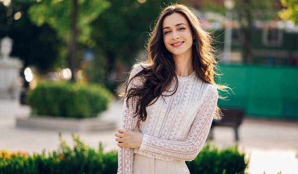 Woman smiling and holding arm outside