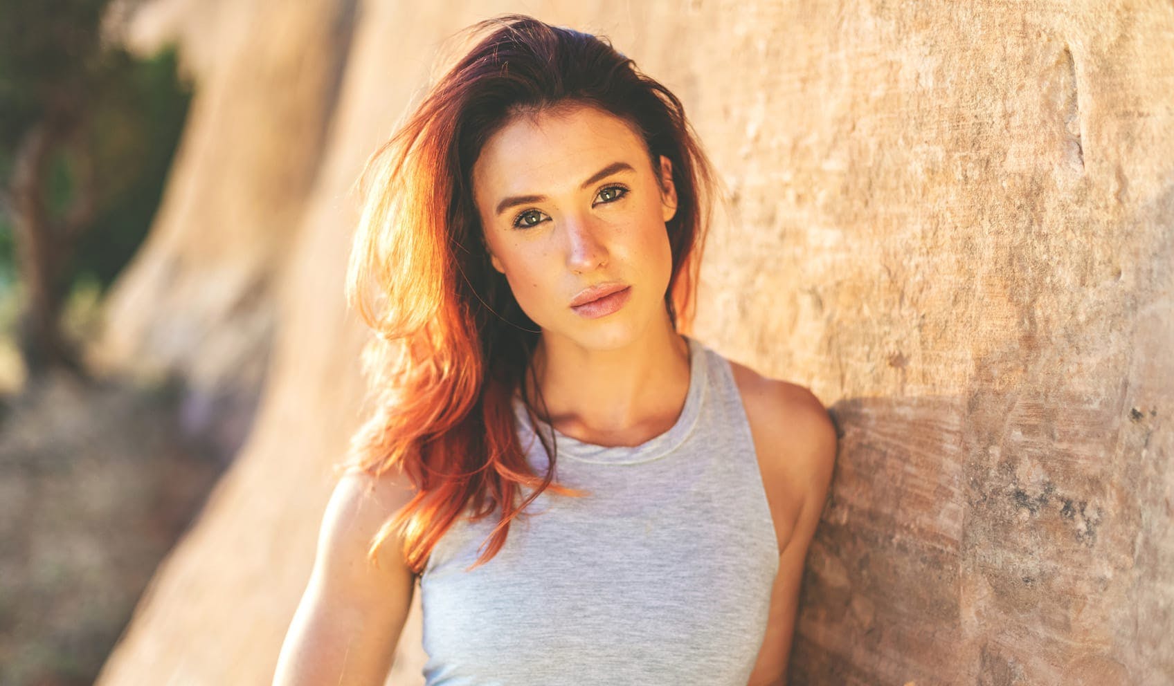 woman leaning against rock wall