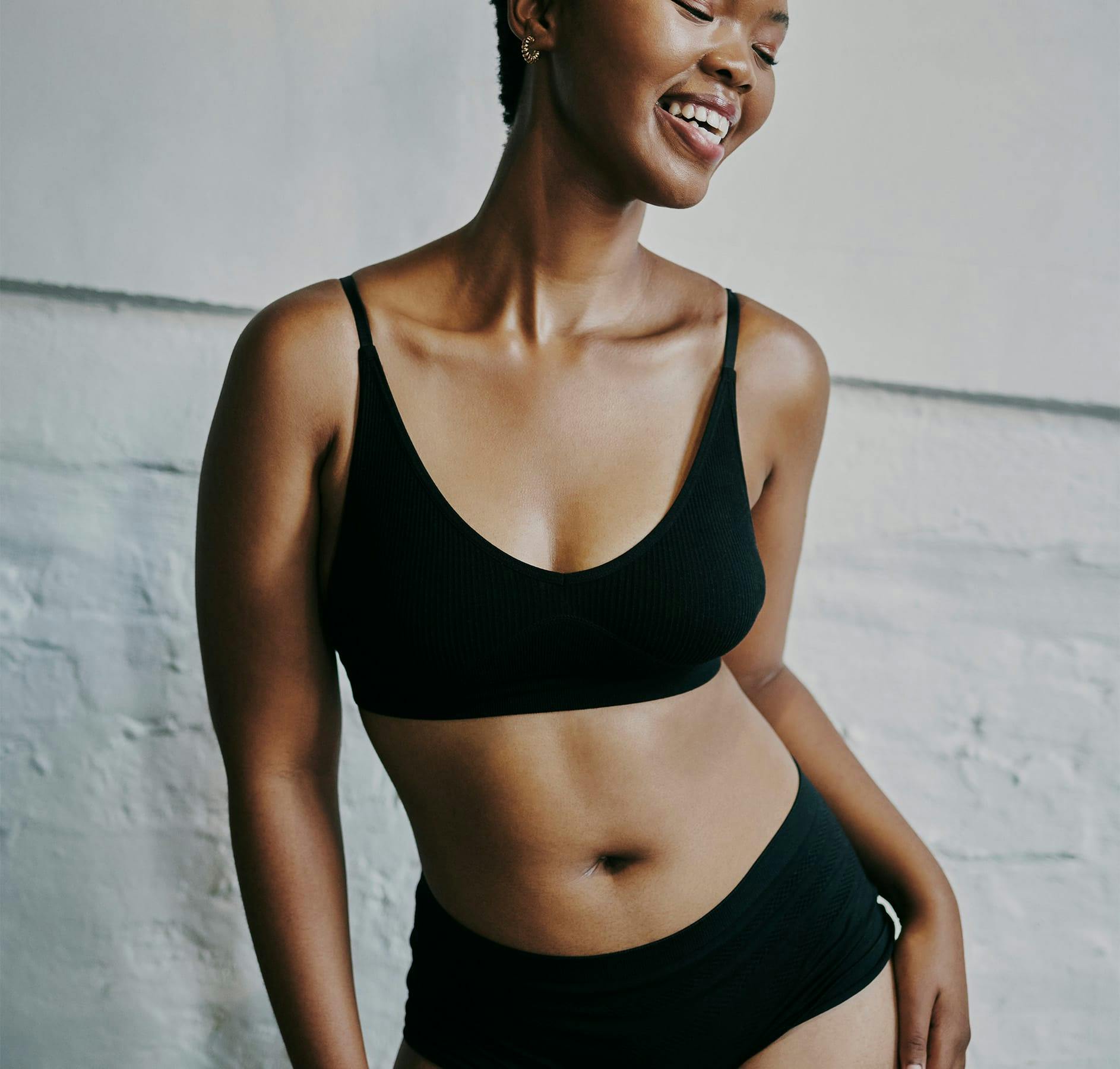 smiling arms at side white brick background